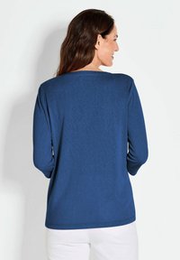 Langärmliges, marineblaues Shirt aus weichem Stoff, mit lässiger Passform und rundem Ausschnitt. Rückansicht zeigt minimale Nähte und glatte Textur.