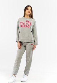 Grauer Sweatshirt- und Sweatpants-Set mit dem auffälligen rosa "ICEBERG"-Text. Weicher Stoff, lässiger Schnitt und weiße Sneaker runden den Look ab.