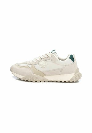 Zapatillas beige que cuentan con materiales de ante y malla, puntera redonda y suela de goma texturizada con relieve en forma de pirámide. Detalle verde en el talón.