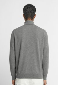 Szary sweter wykonany z miękkiego dzianiny, z wysokim kołnierzem, długimi rękawami oraz ściągaczami u mankietów i u dołu. Minimalistyczny design.