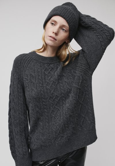 Maglione grigio scuro a maglia grossa con scollatura rotonda e maniche ampie, abbinato a un berretto a coste coordinato. Texture liscia, vestibilità comoda.