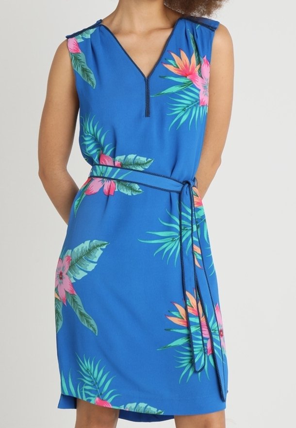 Robe bleue sans manches avec imprimé floral tropical rose et vert, encolure en V, et ceinture assortie nouée à la taille.