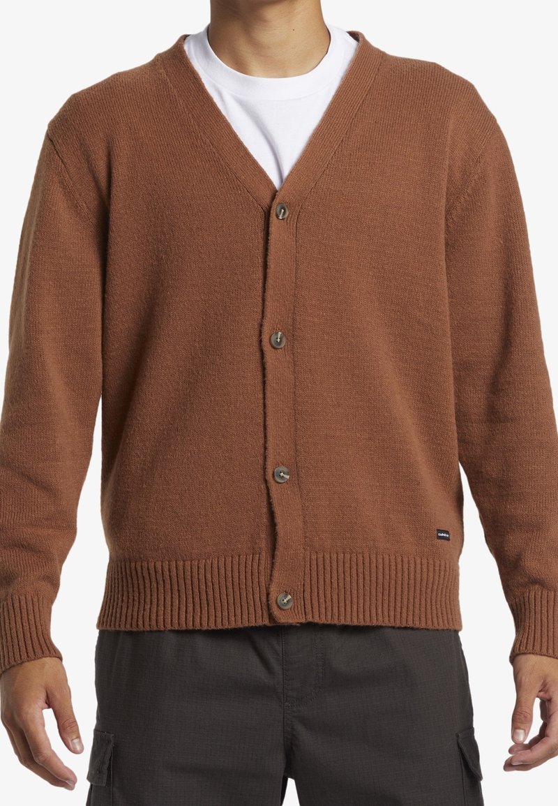Cardigan marron tricoté avec un col en V, une fermeture par boutons, des poignets et un ourlet côtelés, ainsi qu'une petite étiquette de marque en bas.