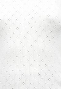 Haut en maille blanche présentant des rayures verticales texturées et de petits motifs en losange, confectionné dans un matériau léger avec une finition douce.