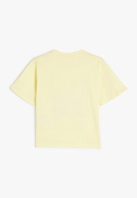 Camiseta de algodón amarilla con mangas cortas, cuello redondo y una textura suave, que presenta un diseño simple y liso sobre un fondo claro.