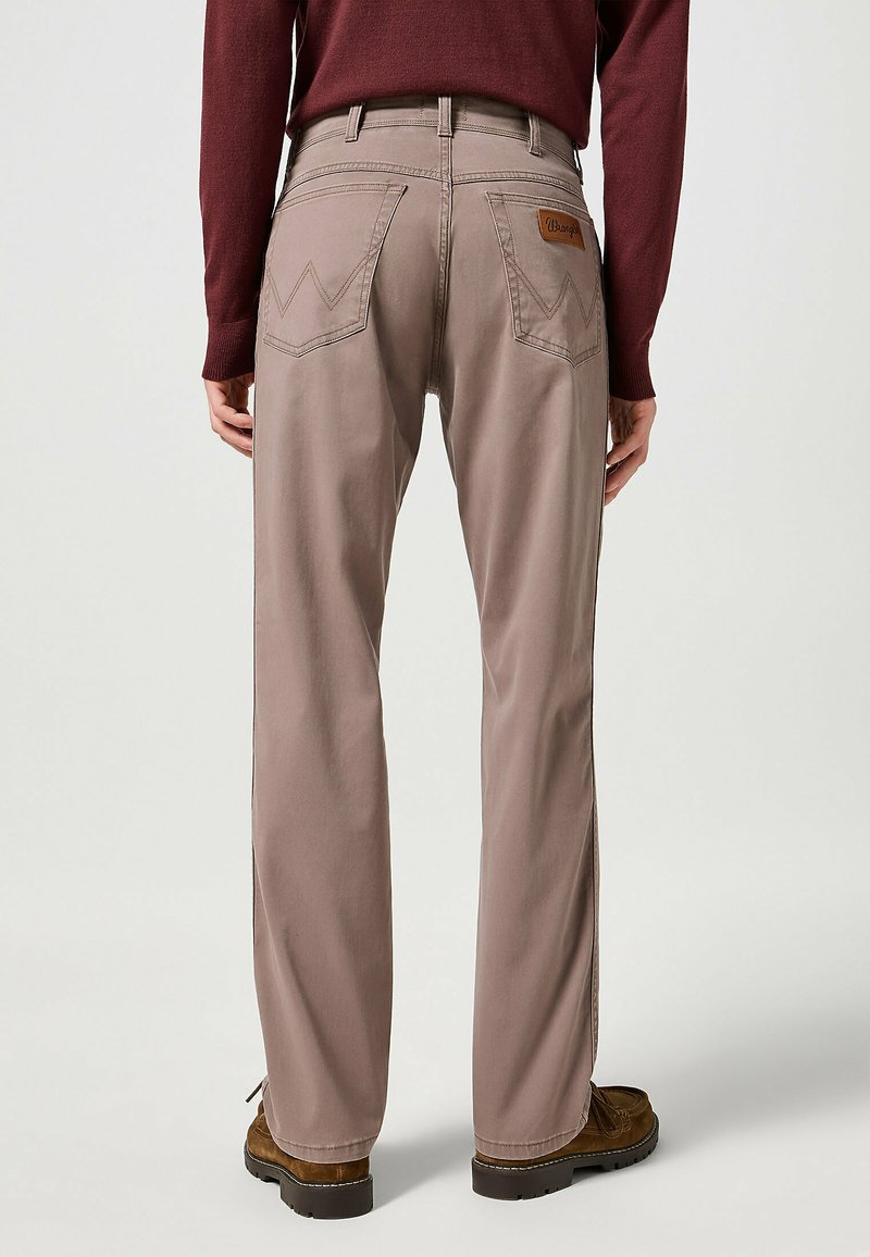 Pantaloni in cotone marrone con design a gamba dritta, dotati di due tasche posteriori, un'etichetta in pelle del marchio e dettagli di cucitura a contrasto.