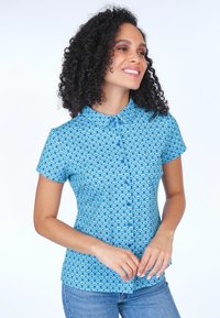 Short-sleeve button-up shirt in light blue fabric with a wave pattern in darker blue. Features a pointed collar and a fitted design.