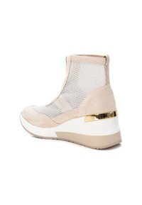 Zapatillas deportivas de cuña beige con parte superior de malla, acentos de ante y un detalle metálico dorado en el talón. La suela es blanca con ribete beige.