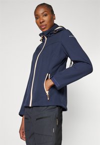 Giacca softshell blu navy con colletto alto, zip rosa e due tasche laterali. Presenta una texture liscia e un cappuccio regolabile con cordino.