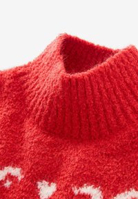 Rode gebreide sweater met een hoge, geribbelde kraag en een zachte, gestructureerde oppervlak met een decoratief wit patroon dicht bij de zoom.