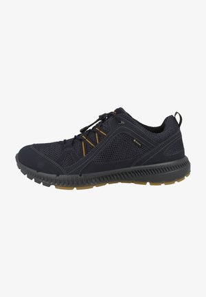 Scarpa sportiva nera e grigia con tomaia in mesh, dettagli gialli sui lacci, linguetta sul tallone e suola in gomma testurizzata per attività all'aperto.
