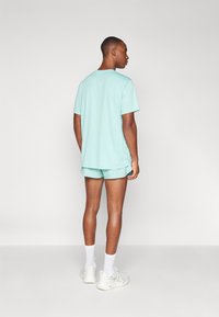 Light blue short-sleeve shirt and matching shorts made of soft fabric, with a relaxed fit and minimal design. Casual athletic style.