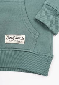 Vihreä luomupuuvillasta valmistettu huppari, jossa on ribbauskutistukset hihansuissa ja helmassa. Hupparissa on etutasku ja kudottu etiketti, jossa lukee "Band of Rascals."