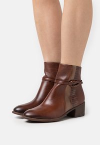 Bottines en cuir marron avec un panneau accent texturé, un détail tressé et un petit talon empilé. Fini lisse avec un bout rond.