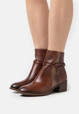 Bottines en cuir marron avec un panneau accent texturé, un détail tressé et un petit talon empilé. Fini lisse avec un bout rond.