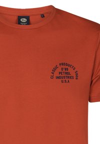 Krátký rukáv, kulatý výstřih oranžové tričko vyrobené z bavlny. Obsahuje tmavě modrý kruhový text: "CLASSIC PRODUCTS D'89 PETROL INDUSTRIES U.S.A."