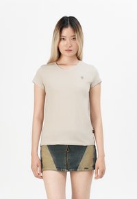 Beige short-sleeved t-shirt with a round neckline and small logo on the chest, paired with a denim skirt featuring color-blocking design.