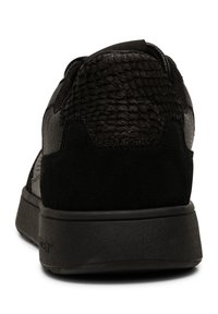 Crna tenisica s teksturiranim upper-om od kože i antilopa, zaobljenog oblika, s podstavljenim ovratnikom i gumenim potplatom. Minimalno brendiranje na peti.