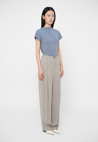 Jasnoniebieski top z krótkim rękawem w połączeniu z szerokimi spodniami w biało-beżowe pionowe paski, z zapięciem na guzik i gładką teksturą.
