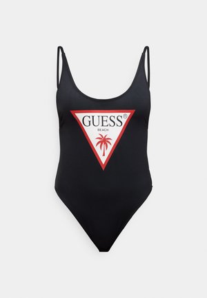 Black one-piece swimsuit with thin straps, featuring a red and white triangular logo design that includes "GUESS BEACH" and a palm tree graphic.
