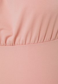 Jasnoróżowa tkanina o gładkiej fakturze, z marszczeniami w talii. Materiał wydaje się elastyczny i dopasowany.