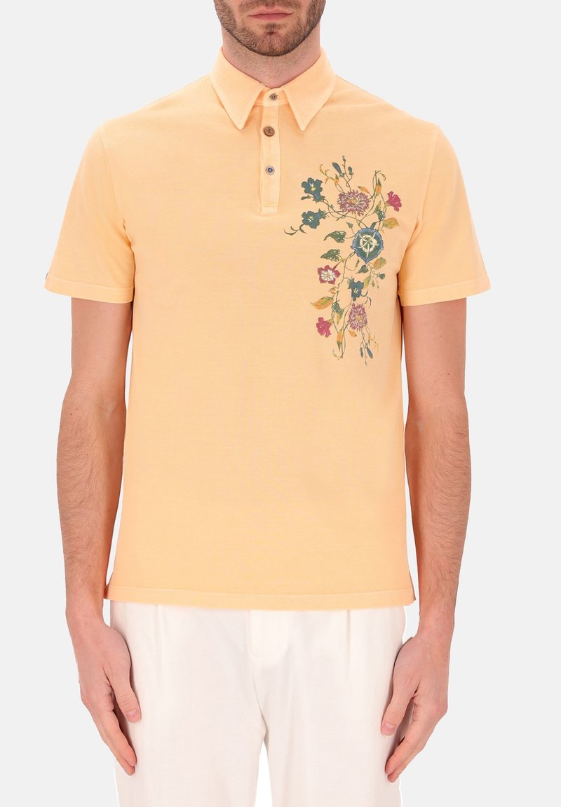 Poloshirt van zachtgeel katoen, met een placket met drie knopen en bloemenborduursel in blauw en roze aan de linkerkant. Korte mouwen.