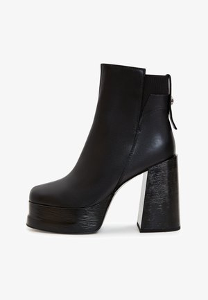 Fekete, sima szintetikus anyagból készült platform bokacipő, lekerekített orral, magas tömbsarokkal és texturált kiemeléssel a sarkon.