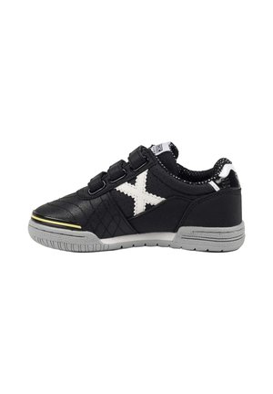 Zapatilla deportiva negra con suela gris, logo blanco en forma de X en el lateral y tres tiras de velcro negras en la parte superior.
