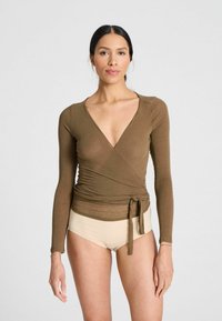 Top avvolgente marrone a maniche lunghe con scollatura a V profonda e fiocco in vita. Tessuto morbido e testurizzato; abbinato a pantaloni beige a vita alta.