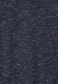 Mörkblått melerat tyg med små vita streck och svart text som säger "VINYL CLUB" med ytterligare mindre ord ovanför och nedanför.