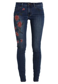 Úzké džíny z tmavého denimu s květinovou výšivkou v červené a zelené barvě na levé noze. Mají tradiční pětikapsový střih.
