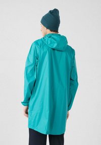 Giacca turchese impermeabile con cappuccio, maniche lunghe e polsini elastici; texture liscia e design al ginocchio. Completata da un berretto aderente.