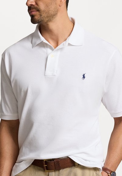 Polo shirt blanche en tissu texturé, dotée d'une patte de boutonnage à trois boutons, d'un col doux et d'un petit logo bleu sur la poitrine gauche.