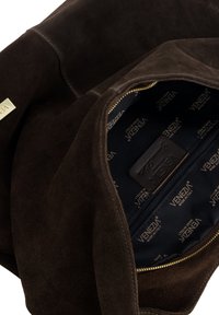 Bruine suède handtas met een gouden ritssluiting, voorzien van een ruim interieur bekleed met marineblauwe stof en een leren label met merknaam.