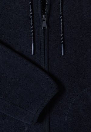 Veste polaire bleu marine avec fermeture éclair intégrale, deux cordons de serrage avec embouts en plastique et manches longues repliées sur le devant.