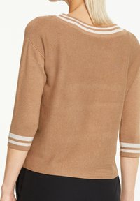 Pull en tricot marron à coupe décontractée, avec des manches trois-quarts et des accents rayés blancs au niveau du col et des poignets.