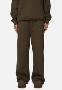 Sweatshirt marron et pantalon de survêtement assorti avec une coupe décontractée. Comprend une poche kangourou et un logo discret sur la jambe gauche. Texture lisse.