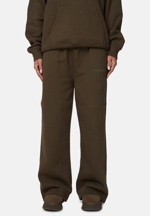 Felpa marrone e pantaloni abbinati in un fit rilassato. Presenta una tasca a marsupio e un logo discreto sulla gamba sinistra. Texture liscia.