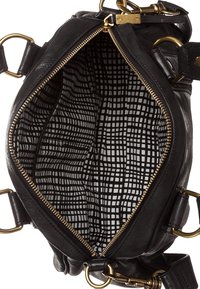 Czarna skórzana torebka o ustrukturyzowanym kształcie z złotym wykończeniem. Wnętrze ma podszewkę w czarno-białą kratę. Zamek błyskawiczny.