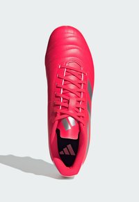 Scarpa da calcio di un brillante colore rosso, realizzata in materiale sintetico, con dettagli cuciti e accenti grigi. Presenta un design con lacci e un colletto imbottito per il comfort.
