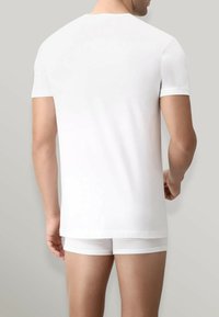 T-shirt bianco a maniche corte realizzato in tessuto morbido, con scollatura rotonda e taglio dritto, indossato con slip bianchi.