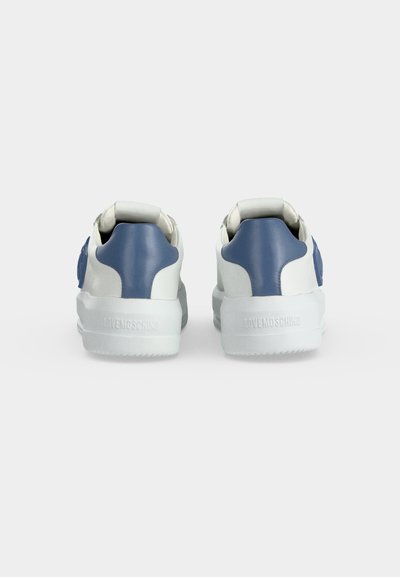 Paire de baskets blanches avec panneaux bleus au talon montrée de dos, avec semelles épaisses blanches et « LOVEMOSCHINO » embossé sur le talon.