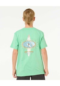 Camiseta de algodón verde con un estampado gráfico de un surfista dentro de una ola, con rayos de sol y el texto "RIP CURL" debajo. Manga corta.