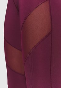 Bordeaux urheiluleggingit, joissa on verkkopaneelin yksityiskohtia. Sujuva pinta ja ompelutiedot. Paneelimuotoilu tarjoaa hengittäviä alueita.