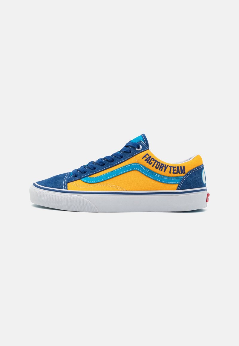 Baskets basses avec bout en daim bleu et talon, côtés en toile jaune, bande bleue et texte "FACTORY TEAM" sur le côté en lettres bleues.