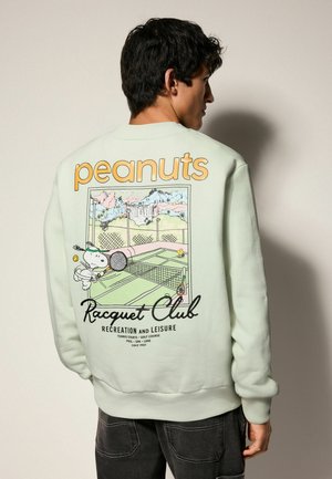 Mint green sweatshirt featuring a large back graphic of Snoopy playing tennis, with "peanuts" and "Racquet Club" text in bold colors.