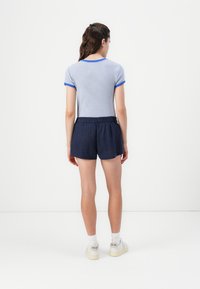 Ριγέ μπλούζα σε μπλε χρώμα με κοντά μανίκια και μπλε περιθώριο, συνδυασμένη με ναυτικές σορτς που διαθέτουν ελαστική μέση και χαλαρή εφαρμογή.