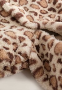 Tessut din blană ecologică cu imprimeu de leopard, având o textură moale, cu modele de bej deschis și maron în diverse tipare. Marginile sunt ușor răsucite.