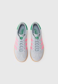 Γκρι σουέτ αθλητικά παπούτσια με ροζ ρίγες, πράσινες λεπτομέρειες στη φτέρνα και σόλα από καουτσούκ χρώματος καρύδας. Διαθέτουν κορδόνια και υφασμένο εσωτερικό.