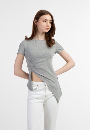 Tricou gri cu dungi, cu mâneci scurte, cu o decupare asimetrică pe o parte, asortat cu blugi albi. Textură netedă, design ajustat.